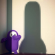 A character from Fall Guys stands scared while a large, rod-shaped shadow looms near.